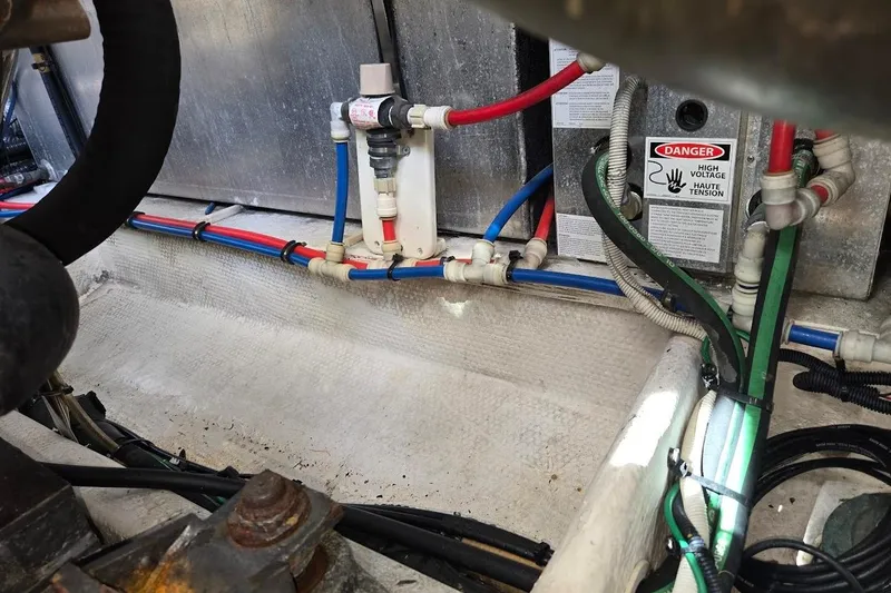 Slide: The Image of Engine compartment of 2009 Mainship Pilot 31 with wiring and high voltage warning. - 77