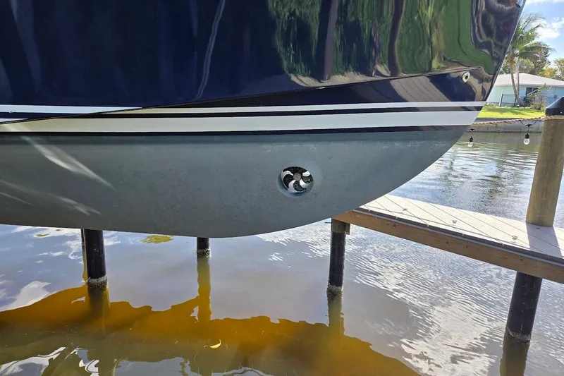 Slide: The Image of 2009 Mainship Pilot 31 boat hull with bow thruster, docked by a wooden pier. - 82