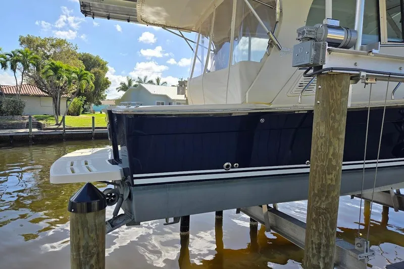 Slide: The Image of 2009 Mainship Pilot 31 boat docked, featuring a sleek design and canopy, in a sunny marina setting. - 83