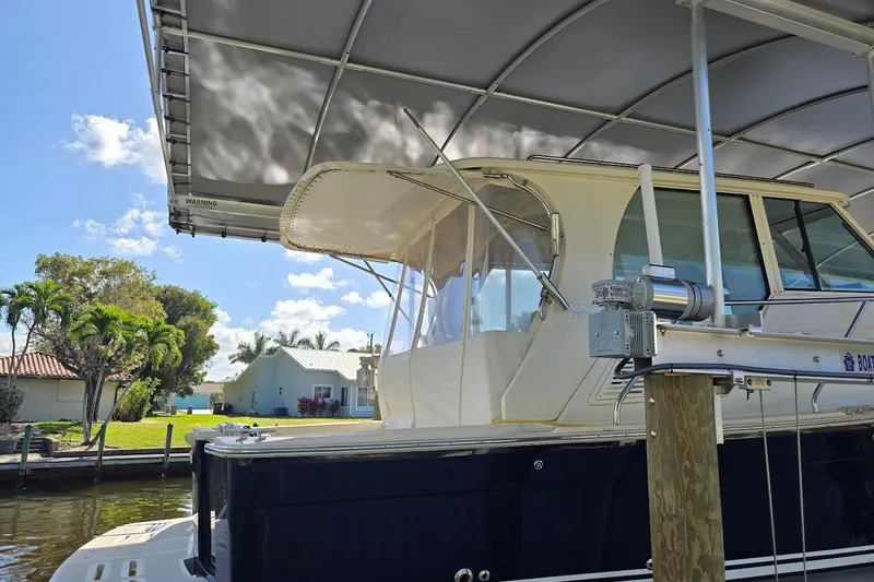 Slide: The Image of 2009 Mainship Pilot 31 docked under canopy, with clear skies and waterfront view. - 84