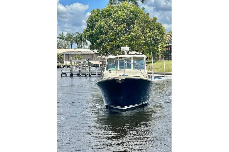 Slide: The Image of 2009 Mainship Pilot 31 boat docked on a calm waterway with lush greenery. - 89