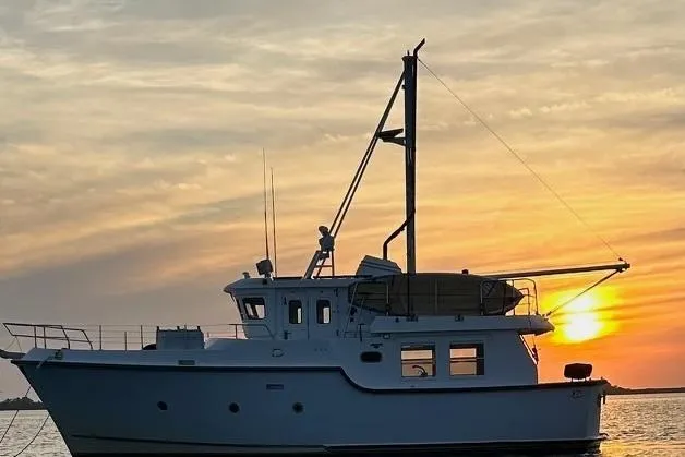 The Image of Nordhavn 40 yacht, 2001 model, silhouetted against a vibrant sunset on the water. - 0
