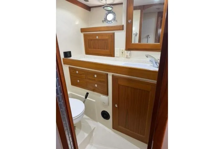 Slide: The Image of 2001 Nordhavn 40 yacht bathroom with wooden cabinets and porthole window. - 14