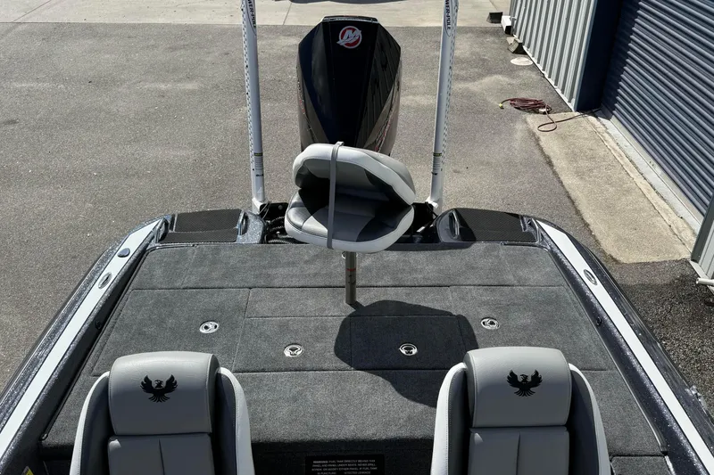 Slide: The Image of 2025 Phoenix 819 ZXL boat interior with seating and motor, parked near a garage. - 13