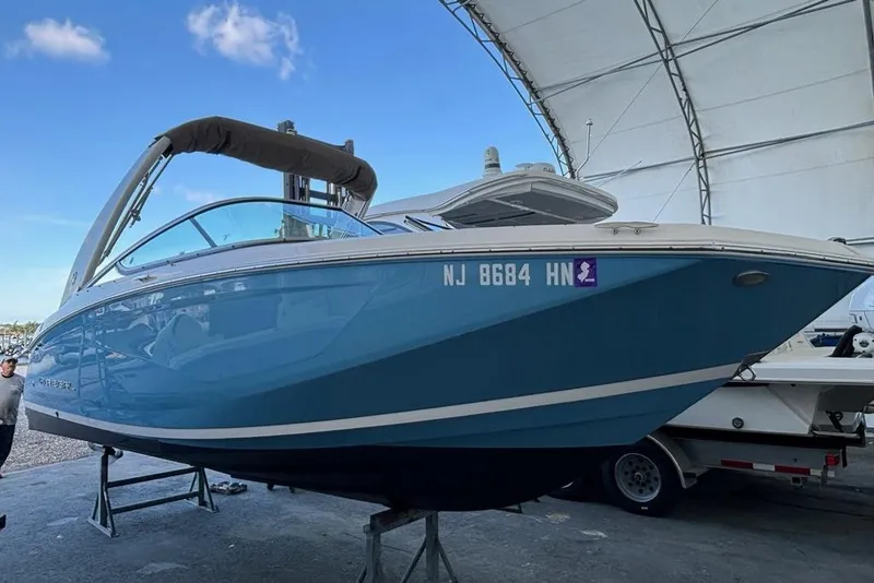 Slide: The Image of 2021 Regal 23 OBX boat in a storage facility, blue hull, registration NJ 8684 HN. - 3