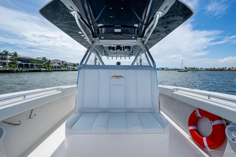 Slide: The Image of 2015 Invincible 42 Open Fisherman boat interior with seating and life preserver on a sunny day. - 24