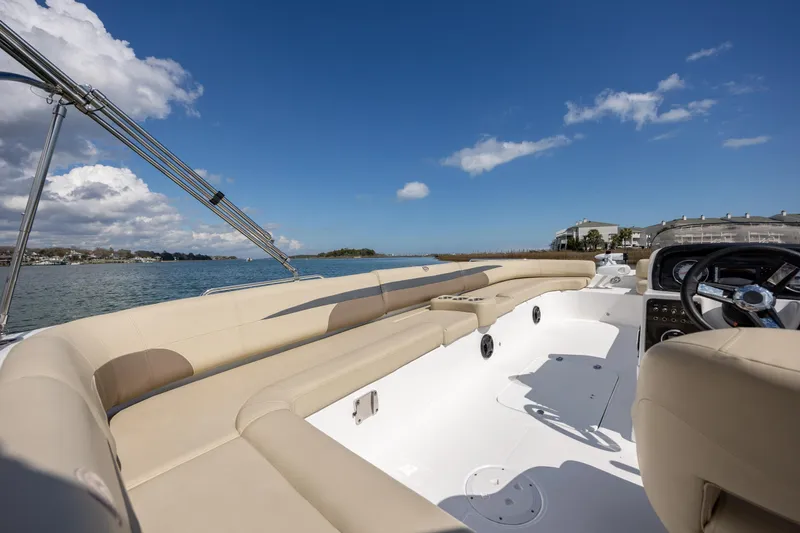 Slide: The Image of 2019 Hurricane SunDeck Sport 201 OB boat interior with beige seating, steering wheel, and open water view. - 13