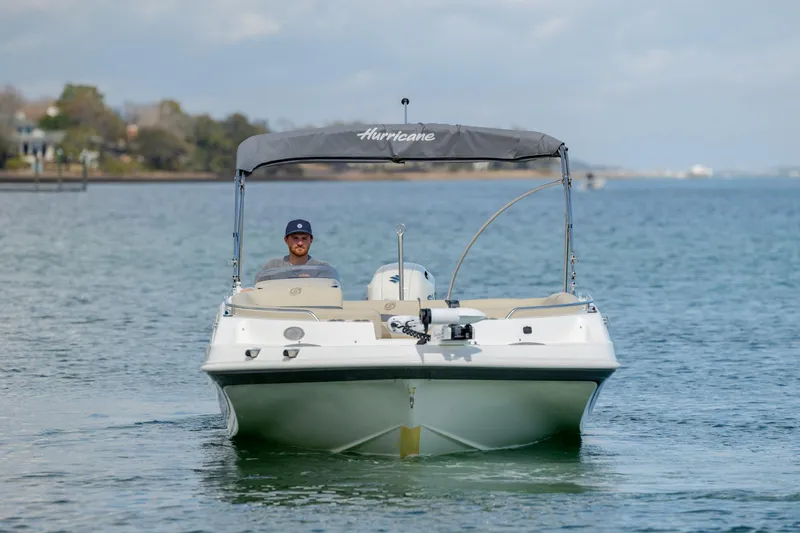 Slide: The Image of 2019 Hurricane SunDeck Sport 201 OB boat on calm water, with canopy and driver. - 8