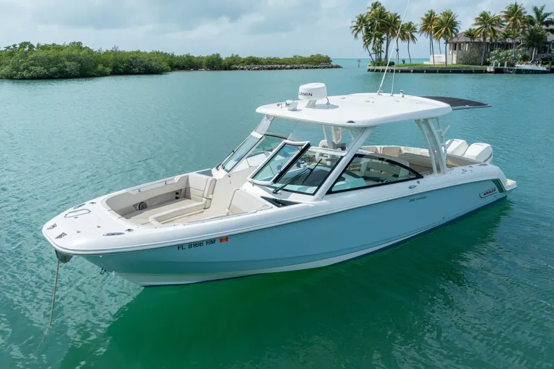 Slide: The Image of 2018 Boston Whaler 320 Vantage boat on calm turquoise water, surrounded by lush greenery. - 1