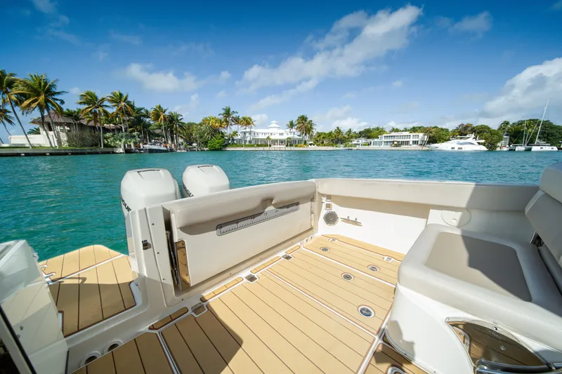 Slide: The Image of 2018 Boston Whaler 320 Vantage boat on serene water with palm trees and luxury homes. - 20