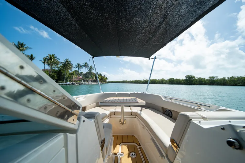 Slide: The Image of 2018 Boston Whaler 320 Vantage boat interior with canopy, overlooking serene water and palm trees. - 29