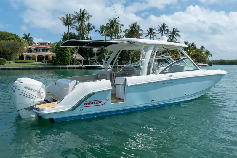 Slide: The Image of 2018 Boston Whaler 320 Vantage boat on water, surrounded by palm trees and luxury homes. - 5