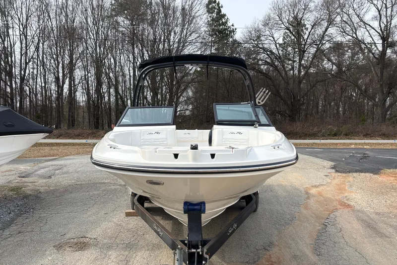 Slide: The Image of 2023 Sea Ray SPX 210 boat on trailer, parked outdoors with trees in background. - 11