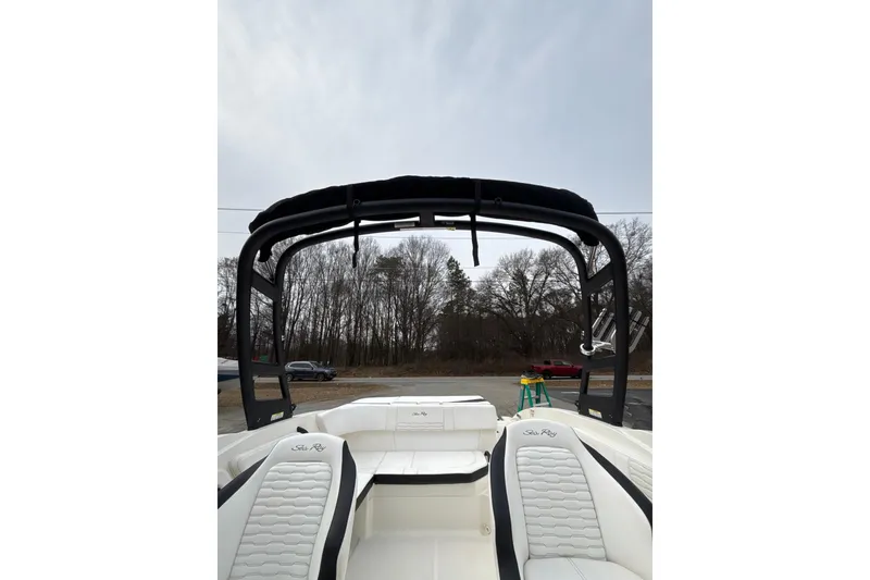 Slide: The Image of 2023 Sea Ray SPX 210 boat interior with seating and canopy, parked outdoors. - 18