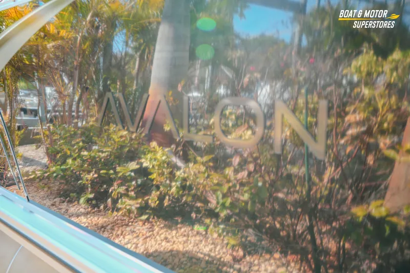 Slide: The Image of 2026 Avalon LSZ Rear Fish boat with reflective surface amidst lush greenery. - 12