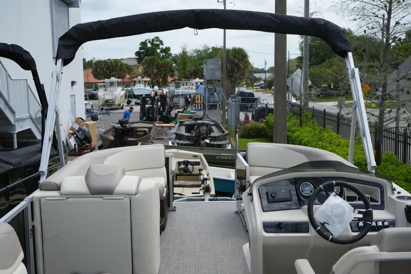 Slide: The Image of 2026 Avalon LSZ Rear Fish 23' boat interior with steering wheel and seating, docked outdoors. - 24