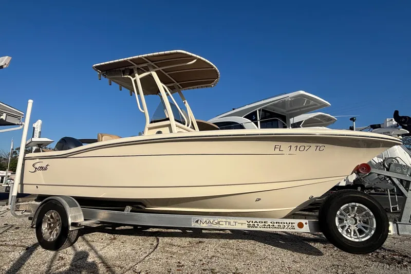 The Image of 2022 Scout 195 Sportfish boat on trailer, beige color, clear blue sky background. - 0
