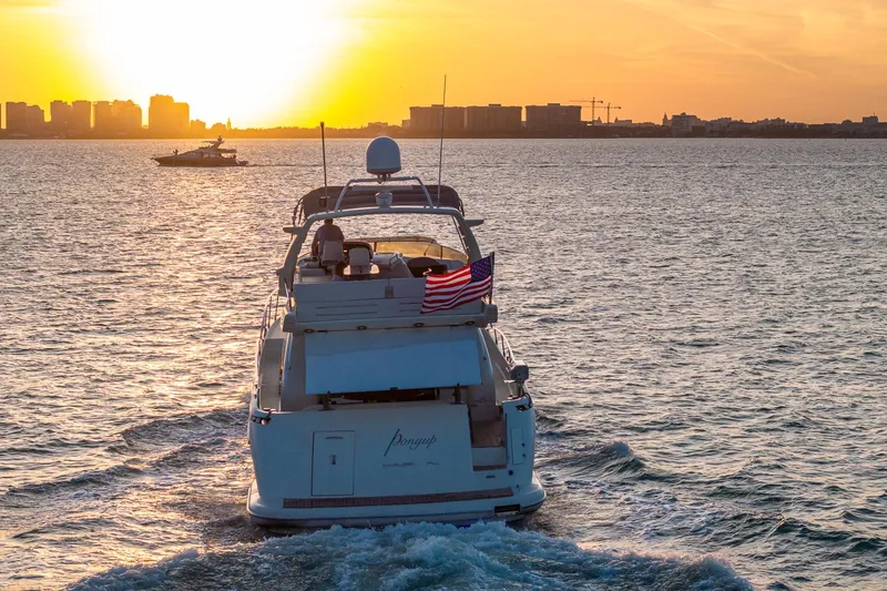 Slide: The Image of Azimut Fly 68 yacht cruising at sunset with city skyline in background. - 15