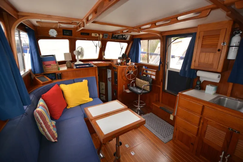 Slide: The Image of Cozy 1998 Monk Trawler interior with wooden furnishings, blue seating, and nautical decor. - 11
