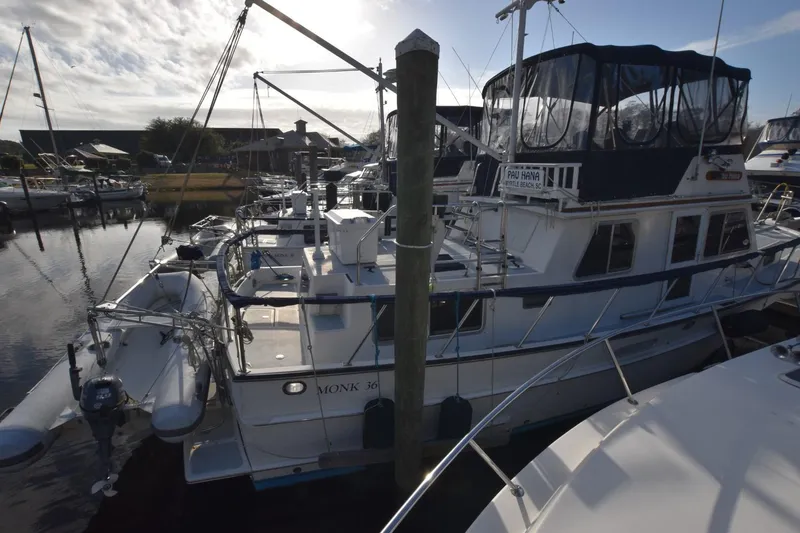Slide: The Image of 1998 Monk Trawler docked at marina, featuring upper deck and dinghy. - 3