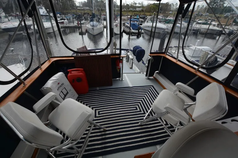 Slide: The Image of 1998 Monk Trawler interior with chairs, striped rug, and marina view. - 7