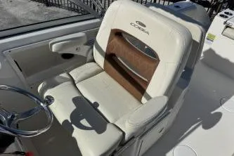 Slide: The Image of 2023 Cobia 220 Dual Console boat seat with steering wheel, featuring beige and brown upholstery. - 10
