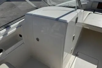 Slide: The Image of 2023 Cobia 220 Dual Console interior, featuring sleek white seating and storage compartments. - 12