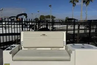 Slide: The Image of 2023 Cobia 220 Dual Console boat with seating, outdoor setting, and palm trees. - 13