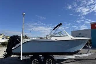 Slide: The Image of 2023 Cobia 220 Dual Console boat on trailer under clear blue sky. - 4