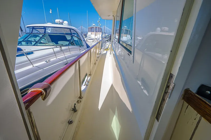 Slide: The Image of 1987 Hatteras 58 Motor Yacht docked, showcasing sleek side deck and marina view. - 13