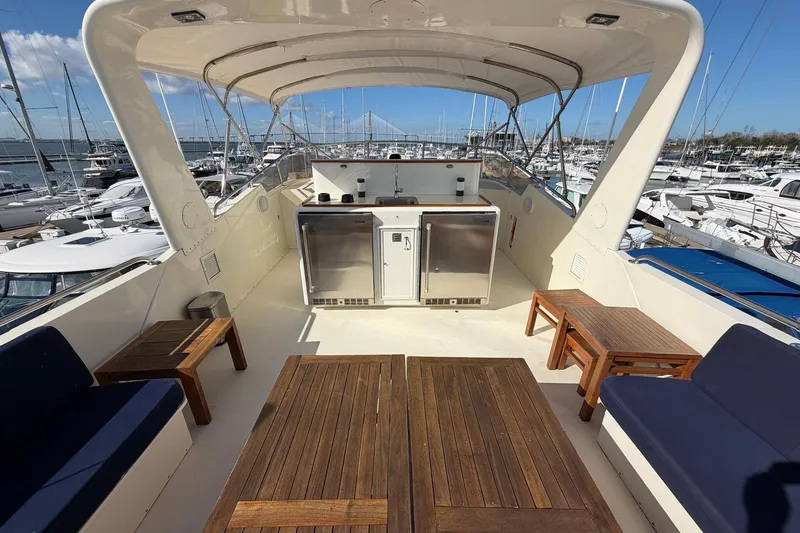 Slide: The Image of 1987 Hatteras 58 Motor Yacht deck with seating, tables, and marina view. - 21
