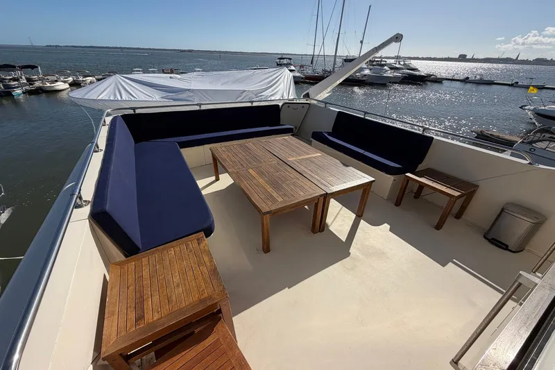 Slide: The Image of Spacious deck of 1987 Hatteras 58 Motor Yacht with wooden furniture and ocean view. - 24