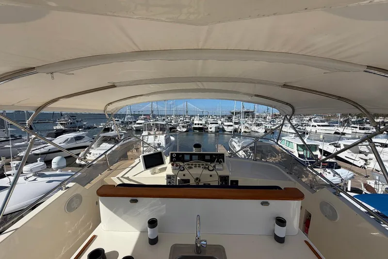 Slide: The Image of 1987 Hatteras 58 Motor Yacht helm view in marina, surrounded by boats. - 26
