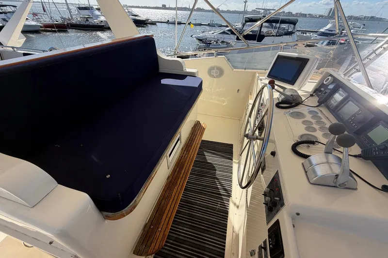 Slide: The Image of 1987 Hatteras 58 Motor Yacht helm with navigation equipment and seating, docked at marina. - 27