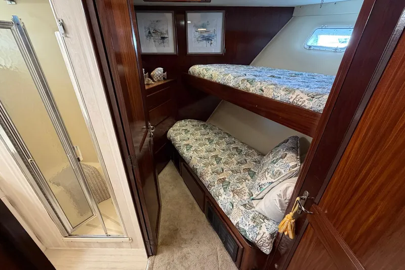 Slide: The Image of Cozy cabin with bunk beds on 1987 Hatteras 58 Motor Yacht, featuring wood paneling and a small window. - 47