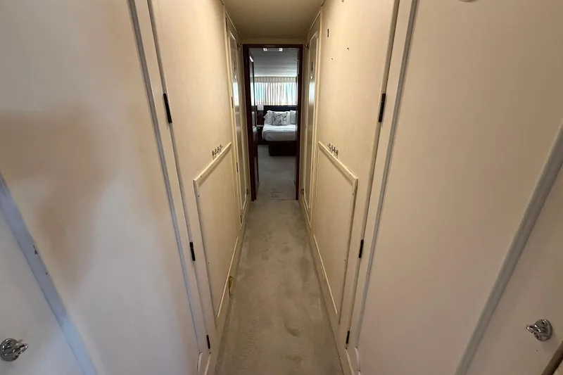 Slide: The Image of Hallway inside 1987 Hatteras 58 Motor Yacht, leading to a bedroom with natural light. - 57