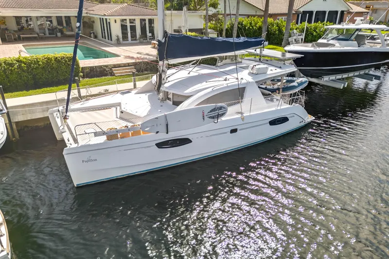 The Image of 2012 Leopard 39 catamaran docked near waterfront homes, featuring sleek design and spacious deck. - 0