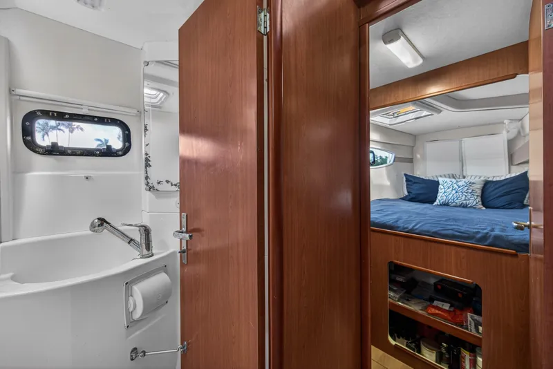 Slide: The Image of Interior of 2012 Leopard 39 yacht showing bathroom and cozy bedroom with blue bedding. - 32