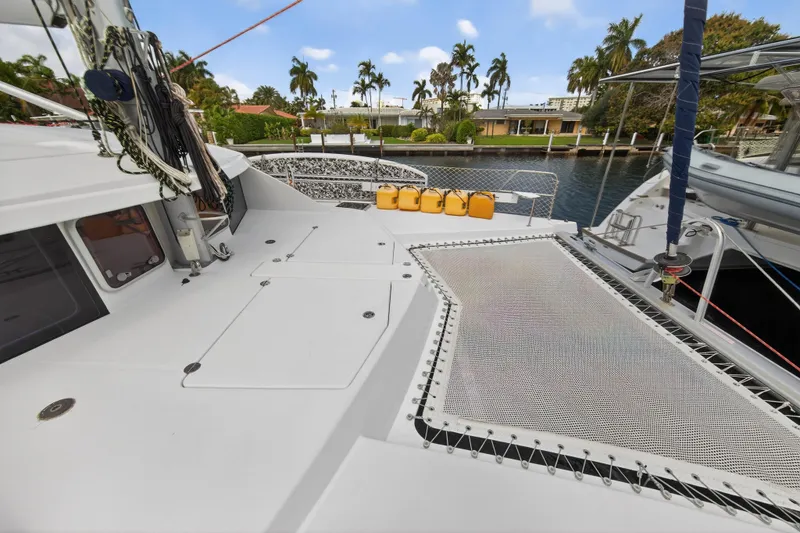 Slide: The Image of 2012 Leopard 39 catamaran deck with netting and yellow fuel containers, docked near palm trees. - 38