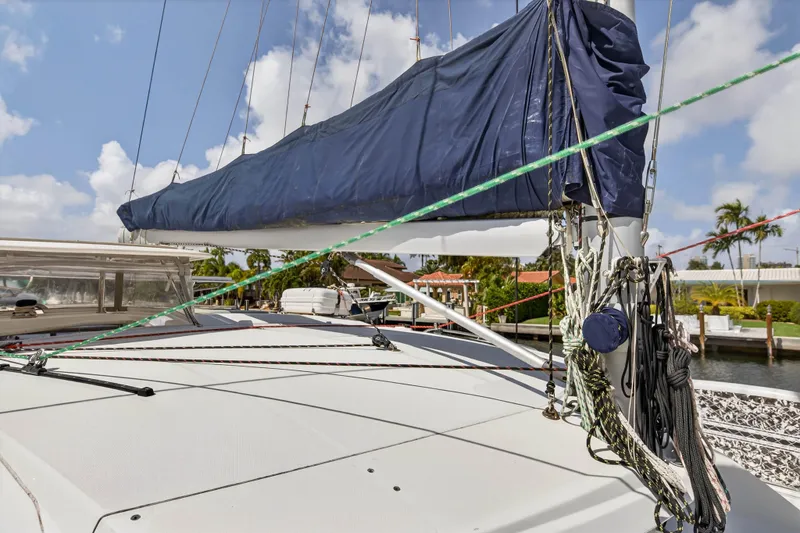 Slide: The Image of 2012 Leopard 39 sailboat deck with rigging and covered sail, docked near palm trees. - 48