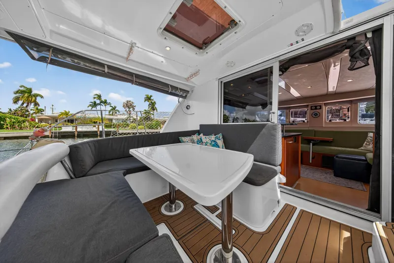 Slide: The Image of Luxurious 2012 Leopard 39 yacht interior with modern seating and table, overlooking serene waterfront. - 5