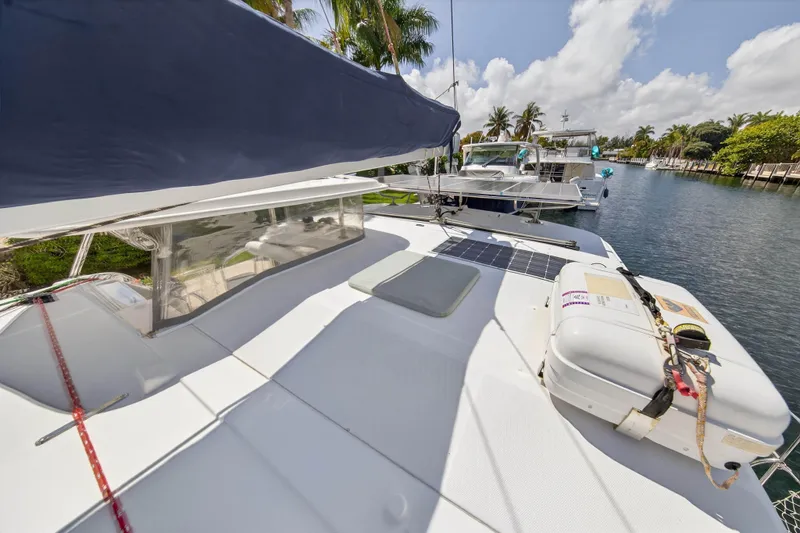 Slide: The Image of 2012 Leopard 39 catamaran docked by palm trees, featuring solar panels and safety equipment. - 64
