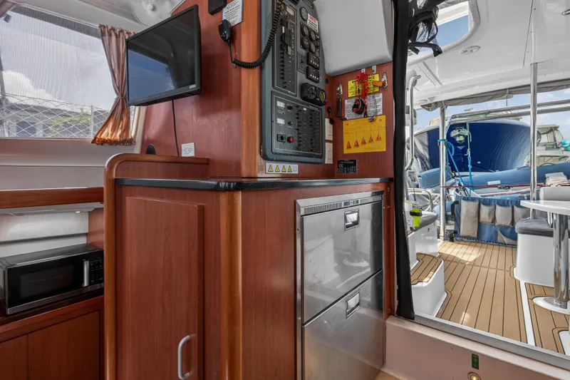 Slide: The Image of Interior of a 2012 Leopard 39 yacht featuring a control panel, microwave, and outdoor seating area. - 79
