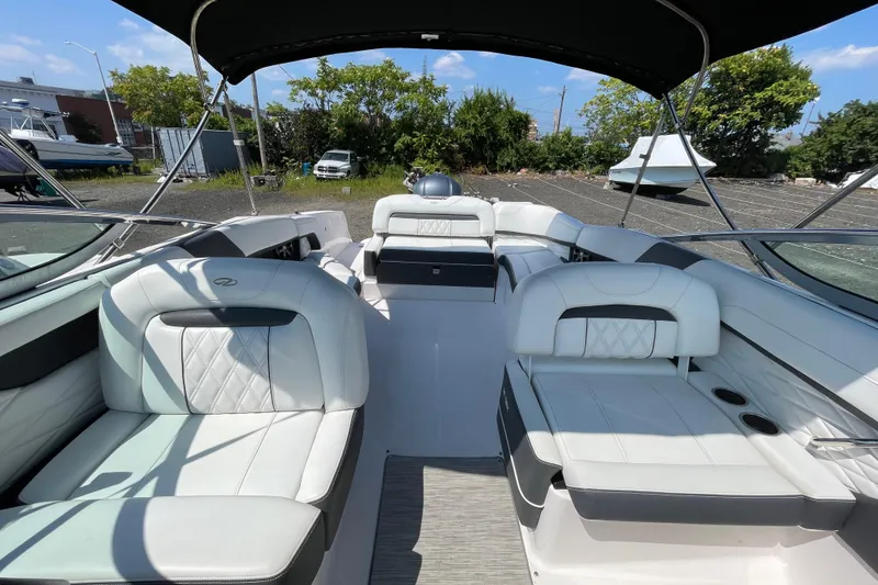 Slide: The Image of 2018 Regal 26 OBX boat interior with white seating and canopy, parked outdoors. - 12