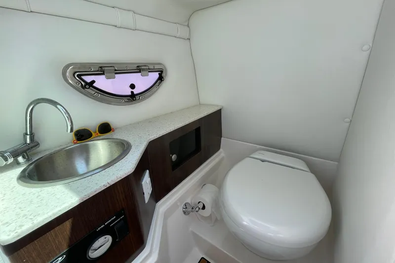 Slide: The Image of 2018 Regal 26 OBX boat bathroom with sink, toilet, and porthole window. - 13