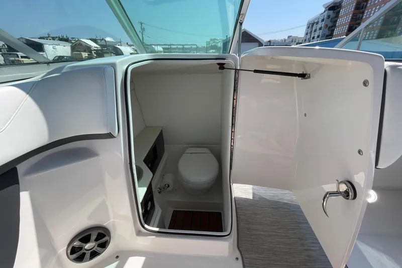Slide: The Image of 2018 Regal 26 OBX boat interior with open bathroom door, showcasing toilet and sink. - 14