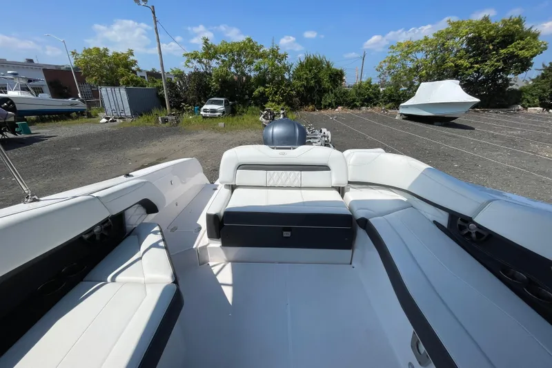 Slide: The Image of 2018 Regal 26 OBX boat interior with white seating, parked outdoors under blue sky. - 5