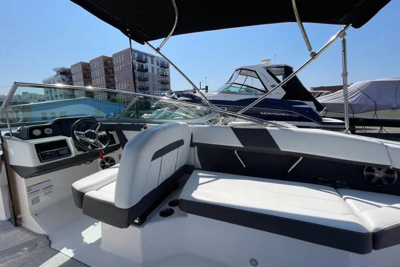 Slide: The Image of 2018 Regal 26 OBX boat interior with modern seating and steering, docked near other boats. - 7