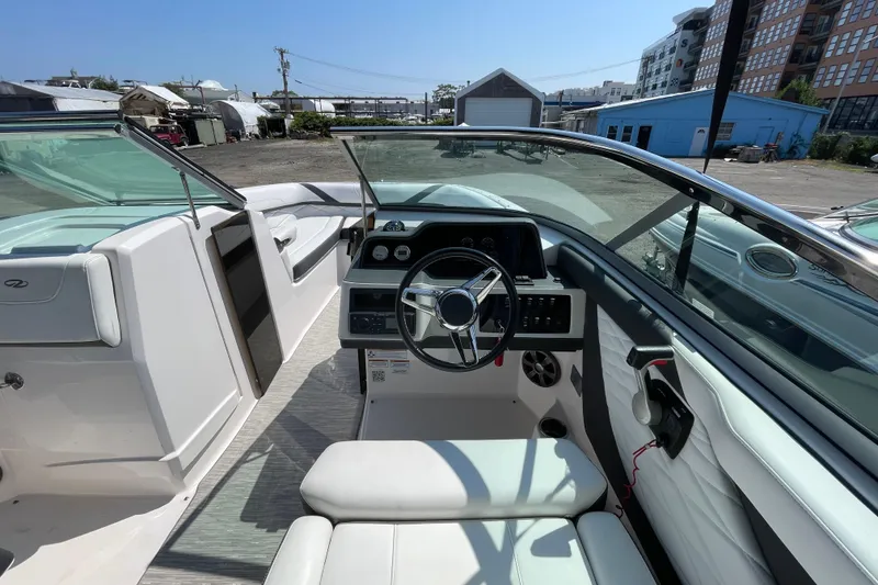 Slide: The Image of 2018 Regal 26 OBX boat interior with steering wheel and seating, docked outdoors. - 9