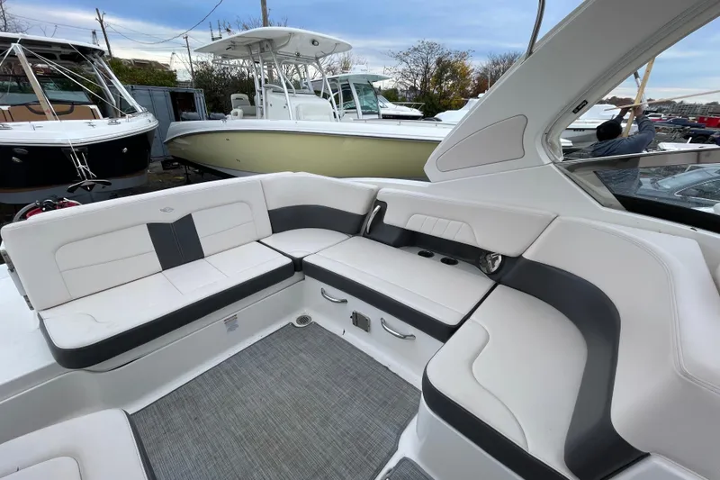 Slide: The Image of 2017 Chaparral 307 SSX boat interior with white and gray seating, docked near other boats. - 2